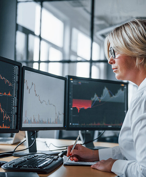 Woman working on her workstation looking at financial graphs