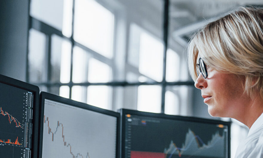 Woman working on her workstation looking at financial graphs